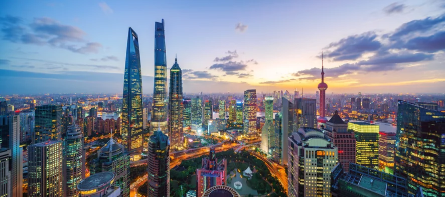 Shanghai skyline at sunset with illuminated skyscrapers.